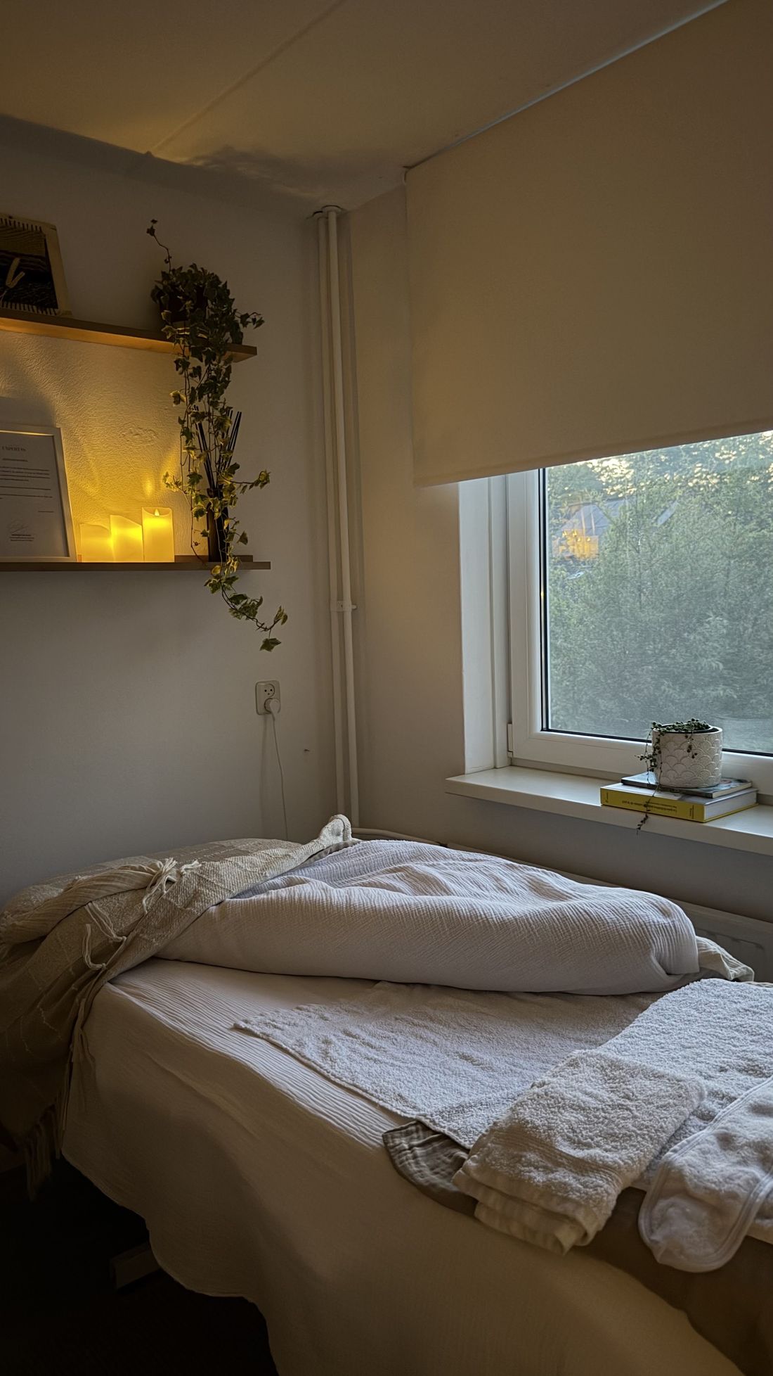 De studio van Dominique: behandelbed met linnen, kaarslicht en een hangplant