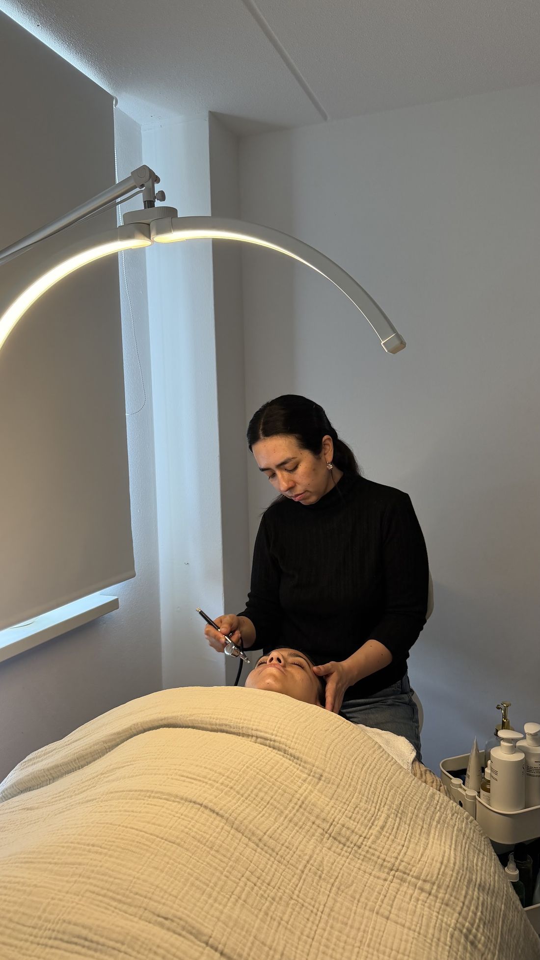 Dominique behandelt een klant onder een gebogen lamp